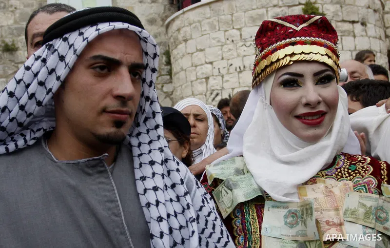 The Palestinian bride and groom Mhaha Salam (R) and Thayer Qasem (L), walk down the street on their wedding day on April 12, 2012 after they traveled from the refugee camp of al-Yarmuk in Syria, to get married in the Wes...