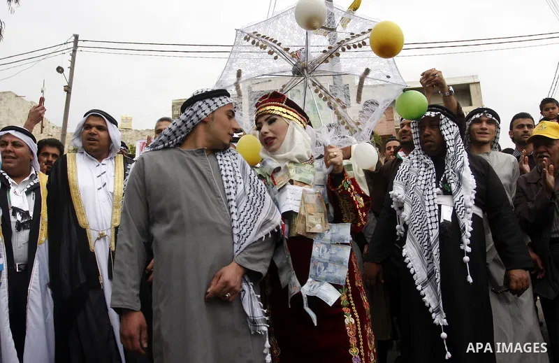 The Palestinian bride and groom Mhaha Salam (R) and Thayer Qasem (L), walk down the street on their wedding day on April 12, 2012 after they traveled from the refugee camp of al-Yarmuk in Syria, to get married in the Wes...