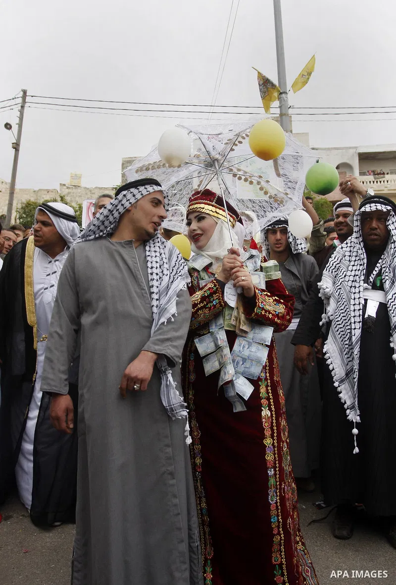 The Palestinian bride and groom Mhaha Salam (R) and Thayer Qasem (L), walk down the street on their wedding day on April 12, 2012 after they traveled from the refugee camp of al-Yarmuk in Syria, to get married in the Wes...