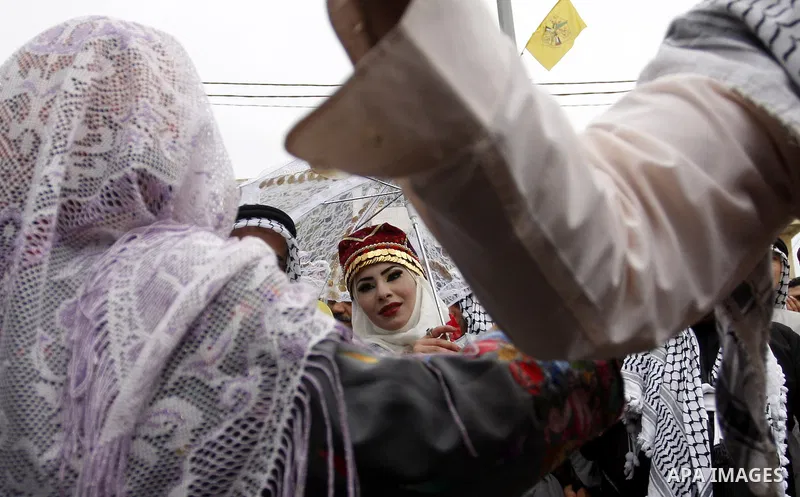 The Palestinian bride and groom Mhaha Salam (R) and Thayer Qasem (L), walk down the street on their wedding day on April 12, 2012 after they traveled from the refugee camp of al-Yarmuk in Syria, to get married in the Wes...