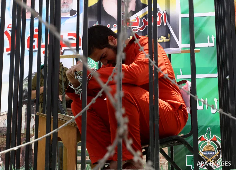 A Hamas supporter acting as a Palestinian prisoner sits in a mock cage during a rally in Jabalya, in the northern Gaza Strip, April 13, 2012, calling for the release of Palestinian prisoners from Israeli jails. Photo by...