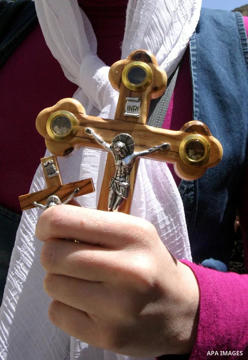 A Christian worshipper holds a cross in the Church of the Holy Sepulchre during the Eastern and Orthodox Church's Good Friday procession in the Old City of Jerusalem April 13, 2012. Photo by Mahfouz Abu Turk