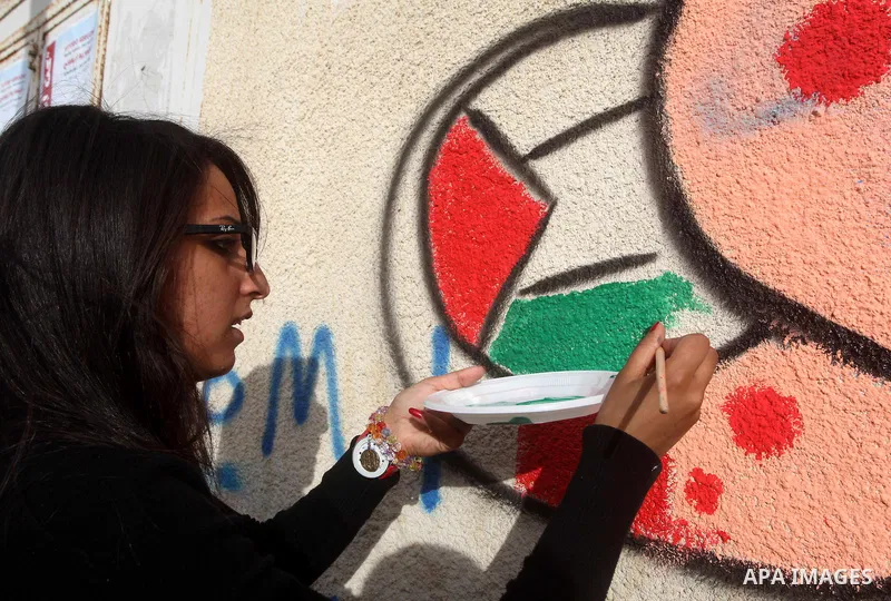 A Palestinian artist puts the final touches on a black and white mural painting dedicated to late Italian activist Vittorio Arrigoni in Gaza City on April 14, 2012, as Gazans marked the first anniversary of his murder in...
