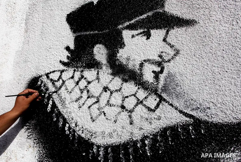 A Palestinian artist puts the final touches on a black and white mural painting dedicated to late Italian activist Vittorio Arrigoni in Gaza City on April 14, 2012, as Gazans marked the first anniversary of his murder in...