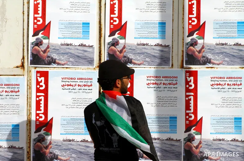 A Palestinian artist puts the final touches on a black and white mural painting dedicated to late Italian activist Vittorio Arrigoni in Gaza City on April 14, 2012, as Gazans marked the first anniversary of his murder in...