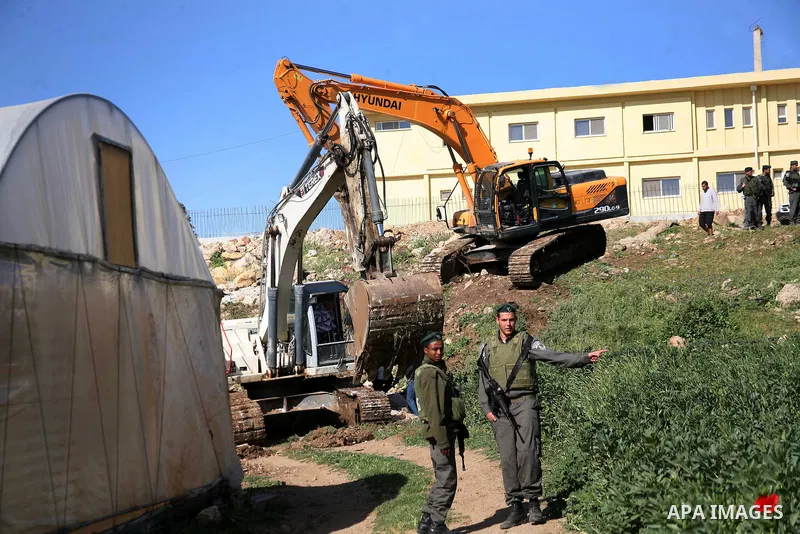 Israeli border police officers stand guard as demolition vehicles destroy a man-made reservoir on a Palestinian farm near the West Bank city of Hebron, on Apr. 16, 2012. Reports state that tensions rose as Palestinian ho...