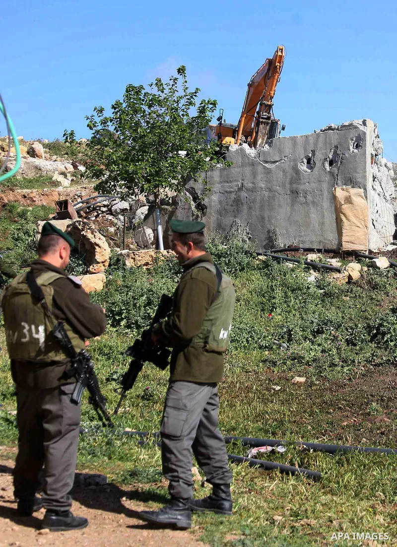 Israeli border police officers stand guard as demolition vehicles destroy a man-made reservoir on a Palestinian farm near the West Bank city of Hebron, on Apr. 16, 2012. Reports state that tensions rose as Palestinian ho...