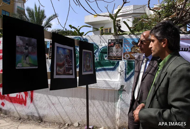 Palestinians look at the murals during a protest during a protest calling for the release of Palestinian prisoners held in Israeli jails inside the grounds of the Red Cross office in Gaza City on April 16, 2012. Some 1,6...