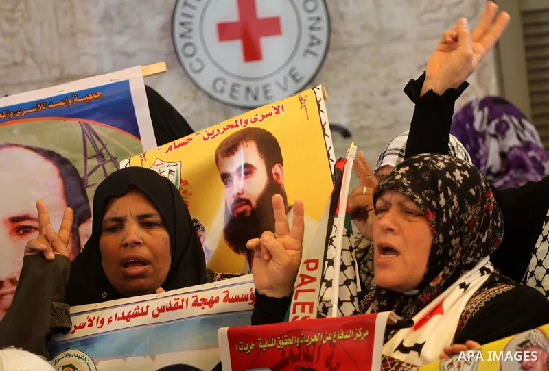 Palestinian women hold up portrait of incarcerated relatives during a protest calling for the release of Palestinian prisoners held in Israeli jails inside the grounds of the Red Cross office in Gaza City on April 16, 20...