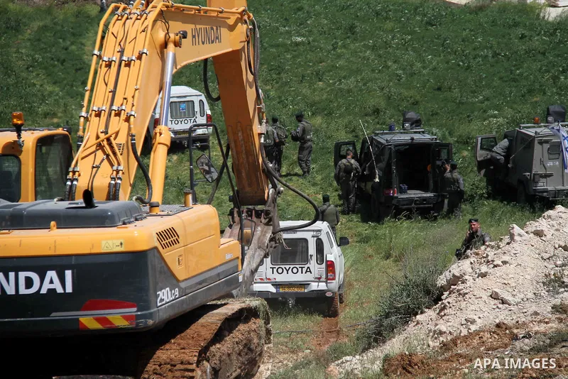 Israeli Border Police stand by as a security bulldozer demolishes a water storage tank owned by the Palestinians in the village of Dura, outside the West Bank city of Hebron, 16 April 2012. The reservoir building was dem...