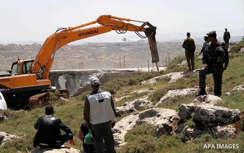 Israeli Border Police stand by as a security bulldozer demolishes a water storage tank owned by the Palestinians in the village of Dura, outside the West Bank city of Hebron, 16 April 2012. The reservoir building was dem...