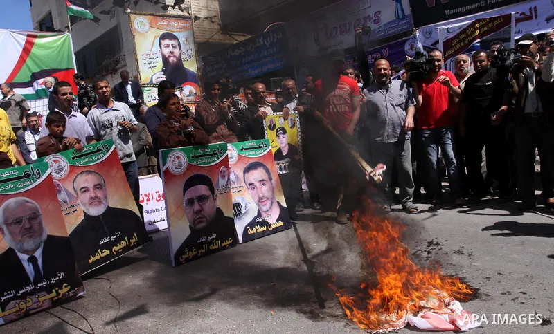 Palestinians burn Israel's national flag during a rally in front of the Red Cross headquarters in Gaza City marking Palestinian Prisoners Day April 17, 2012. The Israeli Prisons Authority said on Tuesday in a written sta...