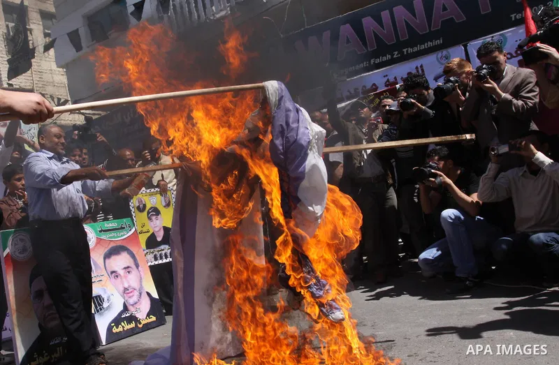 Palestinians burn Israel's national flag during a rally in front of the Red Cross headquarters in Gaza City marking Palestinian Prisoners Day April 17, 2012. The Israeli Prisons Authority said on Tuesday in a written sta...
