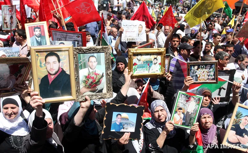 Palestinians hold a photograph of a prisoner jailed in Israel, during a rally marking the annual prisoners' day in the West Bank city of Ramallah, Tuesday, April 17, 2012. Hundreds of Palestinian prisoners held by Israel...