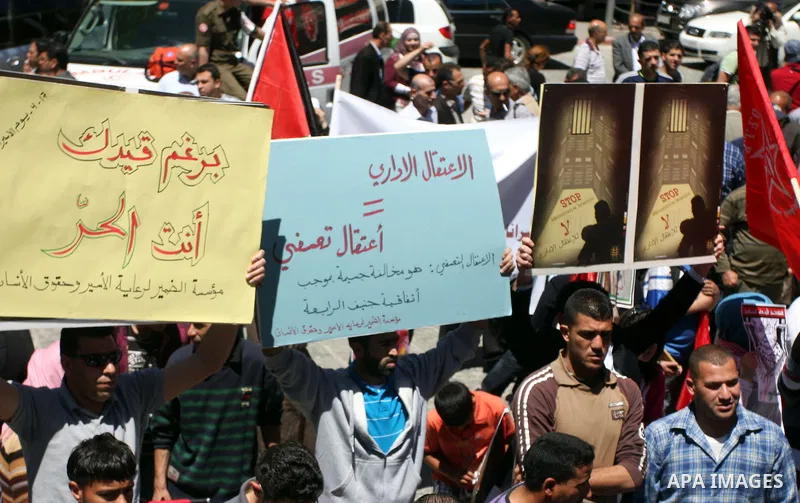 Palestinians hold a photograph of a prisoner jailed in Israel, during a rally marking the annual prisoners' day in the West Bank city of Ramallah, Tuesday, April 17, 2012. Hundreds of Palestinian prisoners held by Israel...