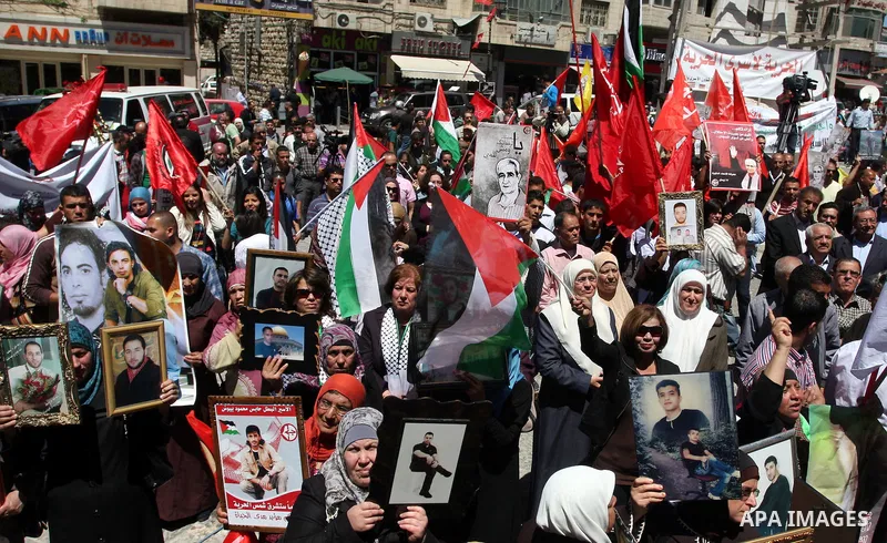 Palestinians hold a photograph of a prisoner jailed in Israel, during a rally marking the annual prisoners' day in the West Bank city of Ramallah, Tuesday, April 17, 2012. Hundreds of Palestinian prisoners held by Israel...