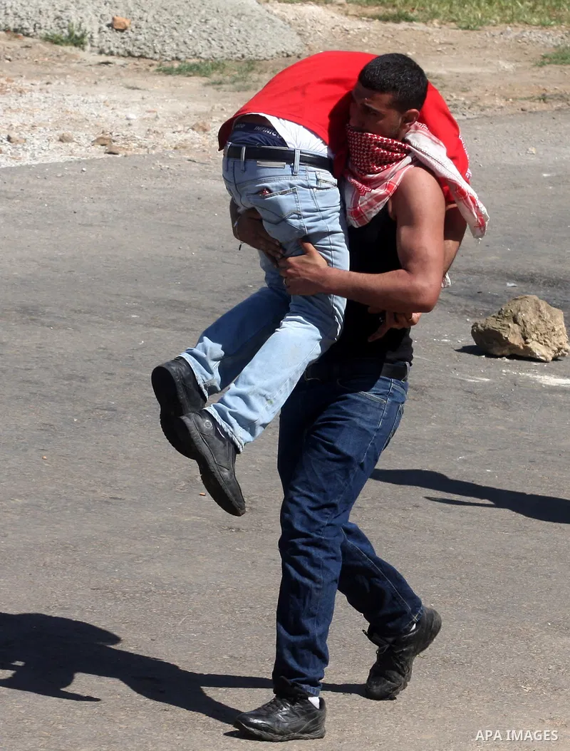 A Palestinian carries an injured demonstrator during clashes with Israeli troops outside Ofer military prison near the West Bank city of Ramallah, on the annual "Prisoners' Day", Tuesday, April 17, 2012. Hundreds of Pale...
