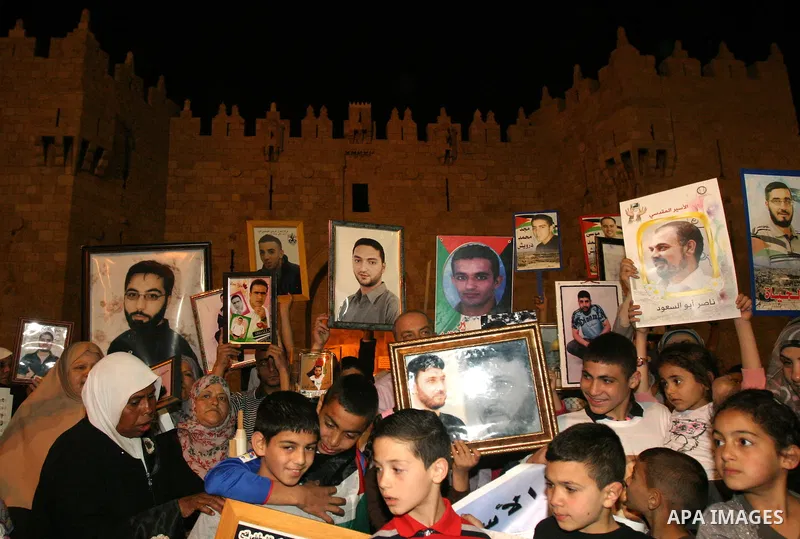 Palestinians hold portraits of relatives jailed in Israeli prisons as they protest to demand for their release during a demonstration to mark Prisoners' Day outside the Damascus gate, in the old city of Jerusalem on Apri...