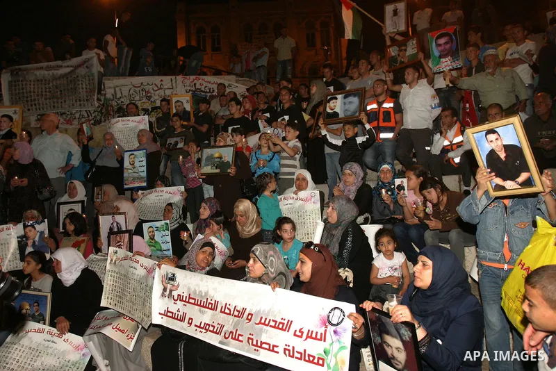 Palestinians hold portraits of relatives jailed in Israeli prisons as they protest to demand for their release during a demonstration to mark Prisoners' Day outside the Damascus gate, in the old city of Jerusalem on Apri...