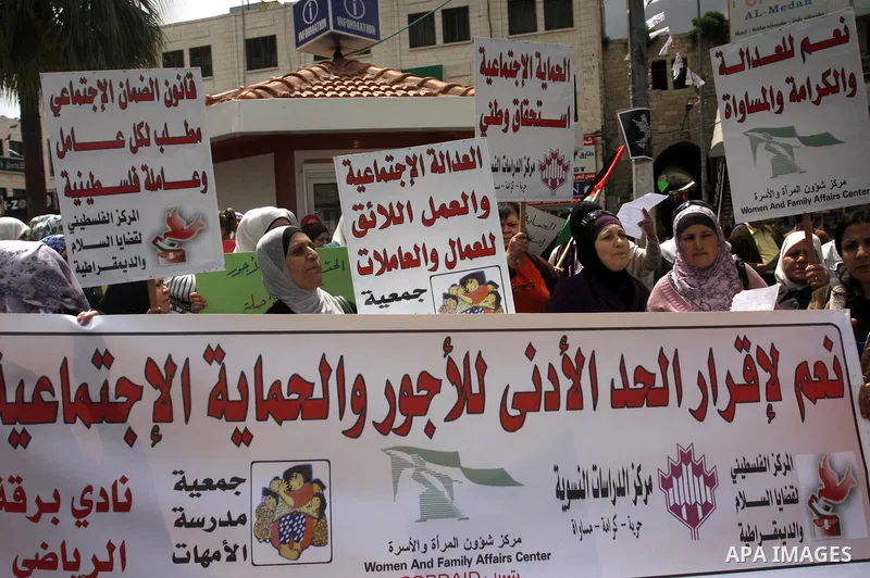 Palestinians hold banners and flags during a march calling for the imposition of the law of collateral social worker for the Palestinian, in April 19, 2012 in the West Bank city of Nablus. Photo by Wagdi Eshtayah.
