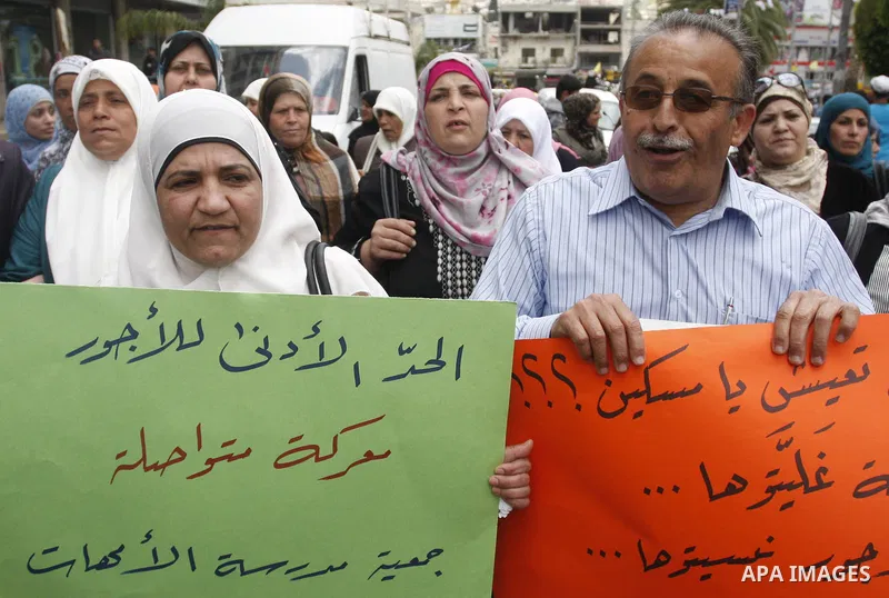 Palestinians hold banners and flags during a march calling for the imposition of the law of collateral social worker for the Palestinian, in April 19, 2012 in the West Bank city of Nablus. Photo by Wagdi Eshtayah.