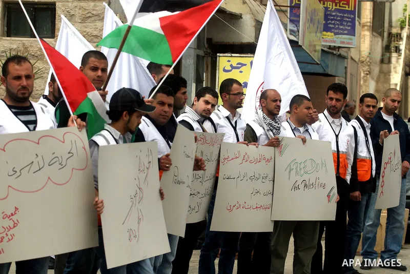 Staff of the Palestinian Red Crescent Society, wave flags and banners during a rally in solidarity with prisoners in Israeli jails, in the West Bank city of Ramallah, April 19, 2012. Photo by Issam Rimawi