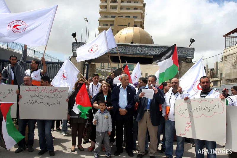 Staff of the Palestinian Red Crescent Society, wave flags and banners during a rally in solidarity with prisoners in Israeli jails, in the West Bank city of Ramallah, April 19, 2012. Photo by Issam Rimawi