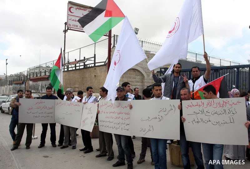 Staff of the Palestinian Red Crescent Society, wave flags and banners during a rally in solidarity with prisoners in Israeli jails, in the West Bank city of Ramallah, April 19, 2012. Photo by Issam Rimawi