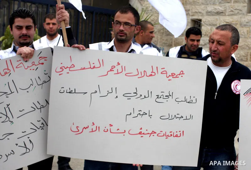 Staff of the Palestinian Red Crescent Society, wave flags and banners during a rally in solidarity with prisoners in Israeli jails, in the West Bank city of Ramallah, April 19, 2012. Photo by Issam Rimawi