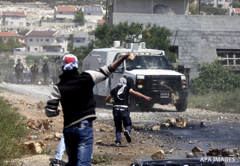 Palestinian protesters throws a stones at an Israeli military digger as it removes a barricade during a demonstration against the expropriation of Palestinian land by Israel in the village of Kafr Qaddum, near the northe...