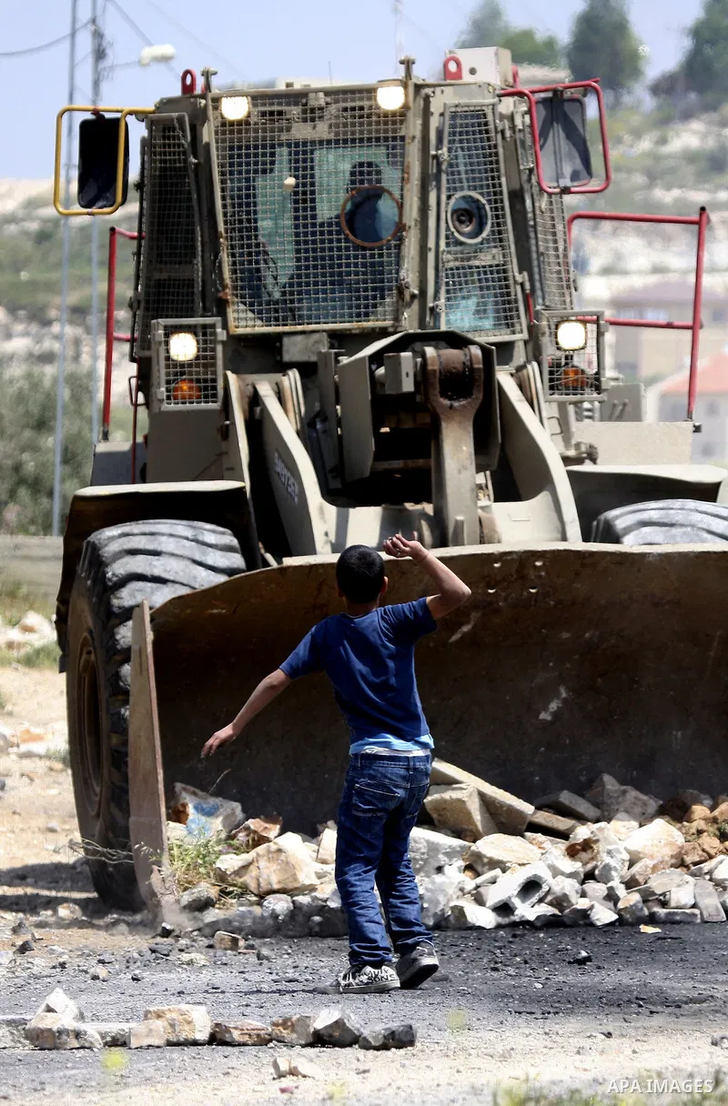 Palestinian protesters throws a stones at an Israeli military digger as it removes a barricade during a demonstration against the expropriation of Palestinian land by Israel in the village of Kafr Qaddum, near the northe...