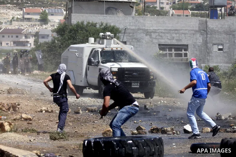 Palestinian protesters throws a stones at an Israeli military digger as it removes a barricade during a demonstration against the expropriation of Palestinian land by Israel in the village of Kafr Qaddum, near the northe...