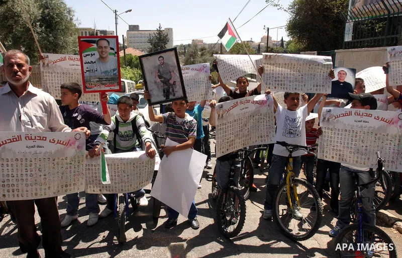 Palestinians hold pictures of a relatives currently being held in an Israeli jail, during a rally outside of the International Red Cross building in east Jerusalem, on April 20, 2012. Photo by Mahfouz Abu Turk