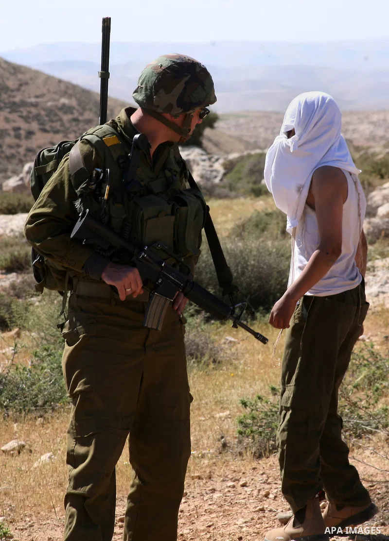 Israeli Jewish settlers look on as Israeli soldiers move Palestinian farmers and shepherds off their land to allow the settlers to farm the land near the Maaon Jewish settlement, just south of the Palestinian village of...