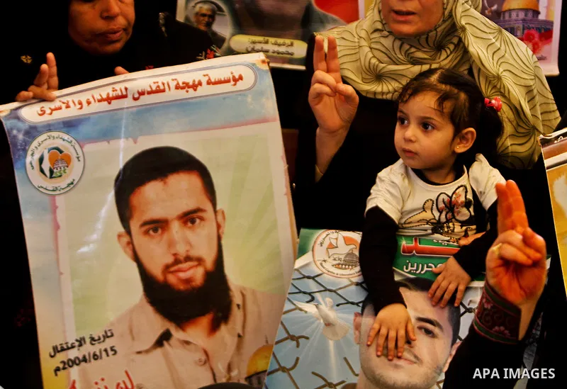 A Palestinian woman holding up a portrait of a jailed loved one takes part in a protest outside the Red Cross offices in Gaza City on April 23, 2012. Photo by Ali Jadallah