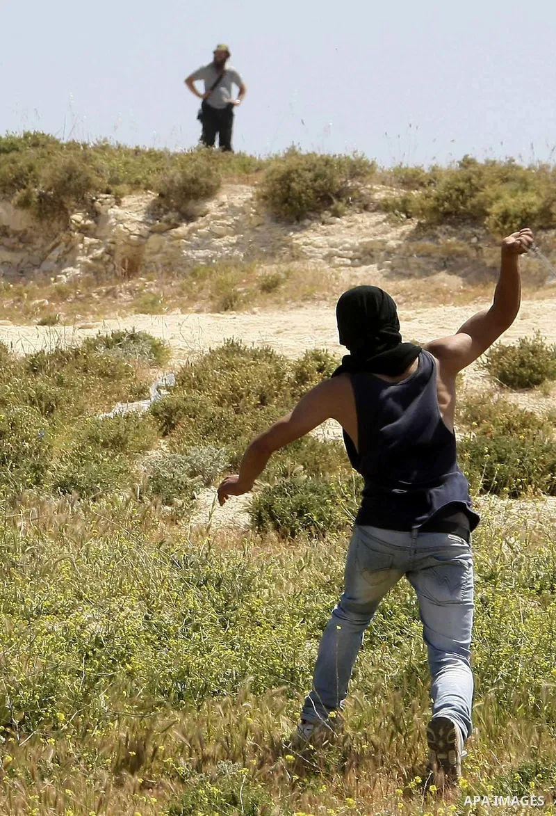 A Palestinian throws a rock toward a Jewish settler during clashes near their school at Oref Village near the West Bank City of Nablus on 23 April 2012 .Israeli settlers from Jewish settlement of Yetshar attacked the sch...