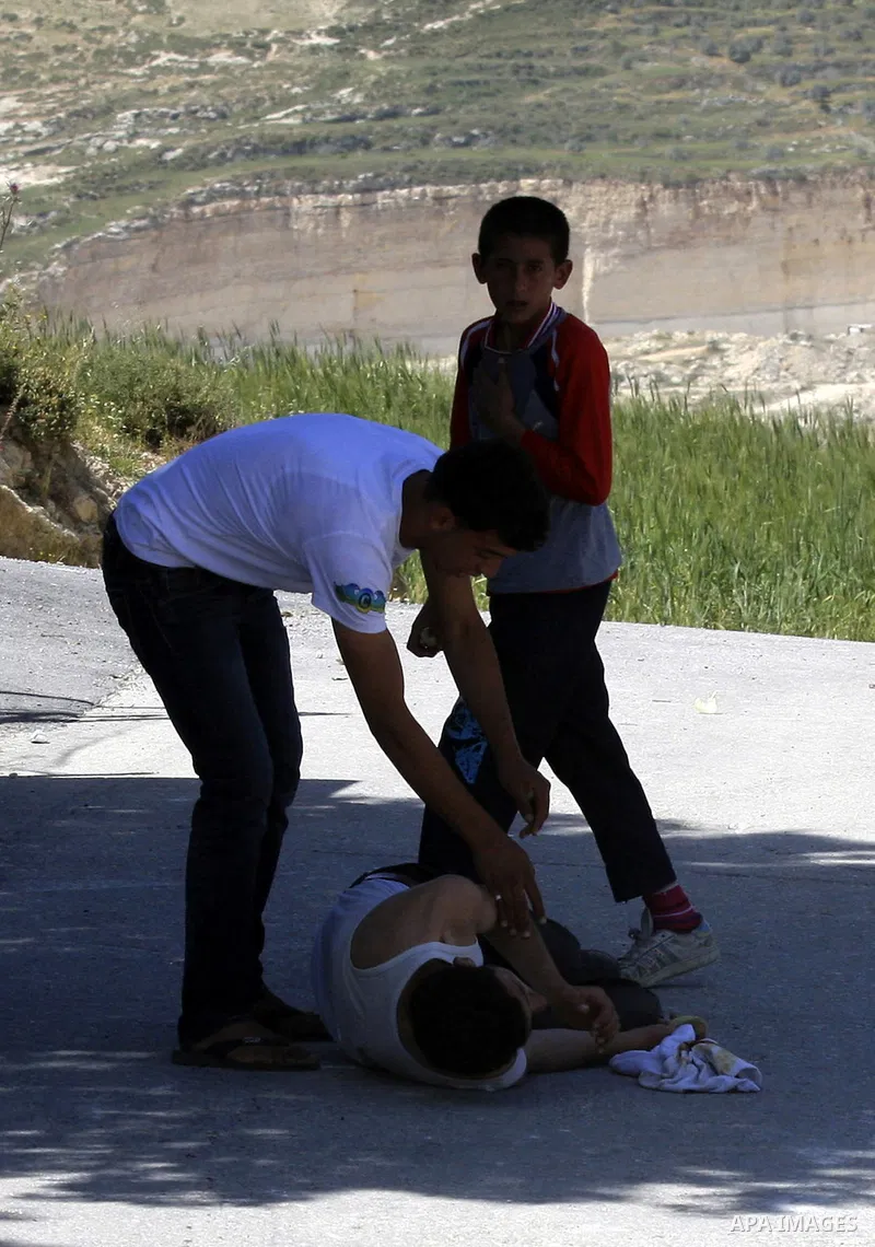 Palestinians carry a wounded demonstrator injured during clashes near their school at Oref Village near the West Bank City of Nablus on 23 April 2012 .Israeli settlers from Jewish settlement of Yetshar attacked the schoo...