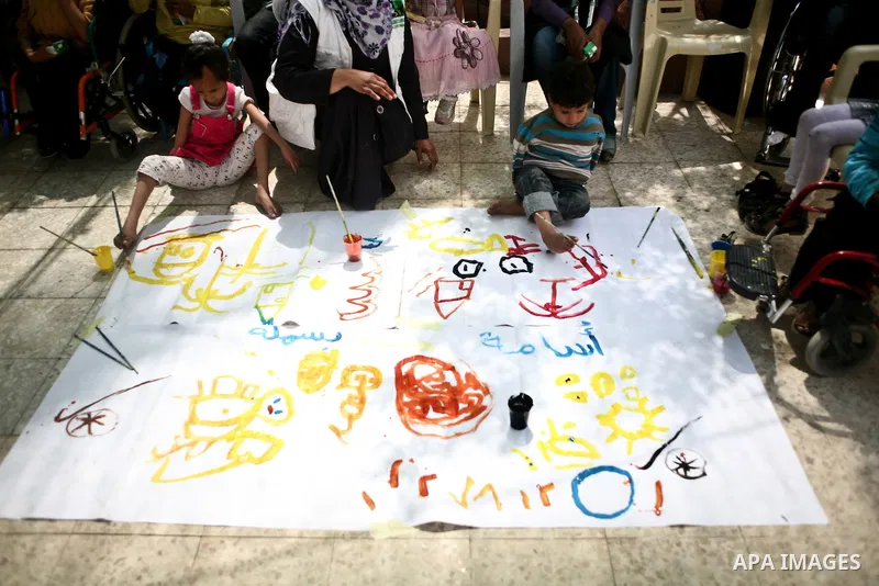 Palestinian disabled children use their feet to draw and paint pictures at a charity association during a celebration in Gaza city on April 23,2012. Photo by Ali Jadallah