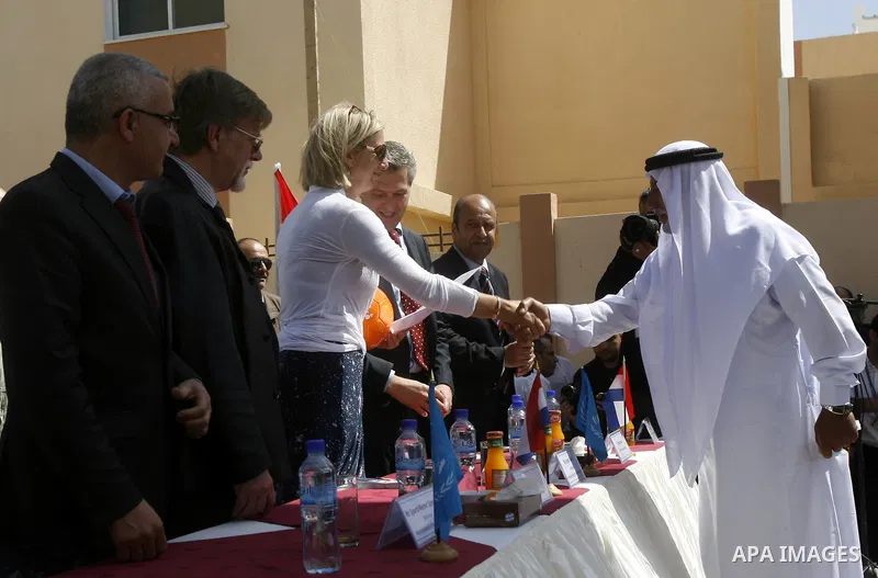 Birgitta Tazelaar, head of Mission of the Netherlands Representation to the Palestinian Authority, watches a Palestinian man react during a ceremony distributing new homes in Khan Younis in the southern Gaza Strip April...