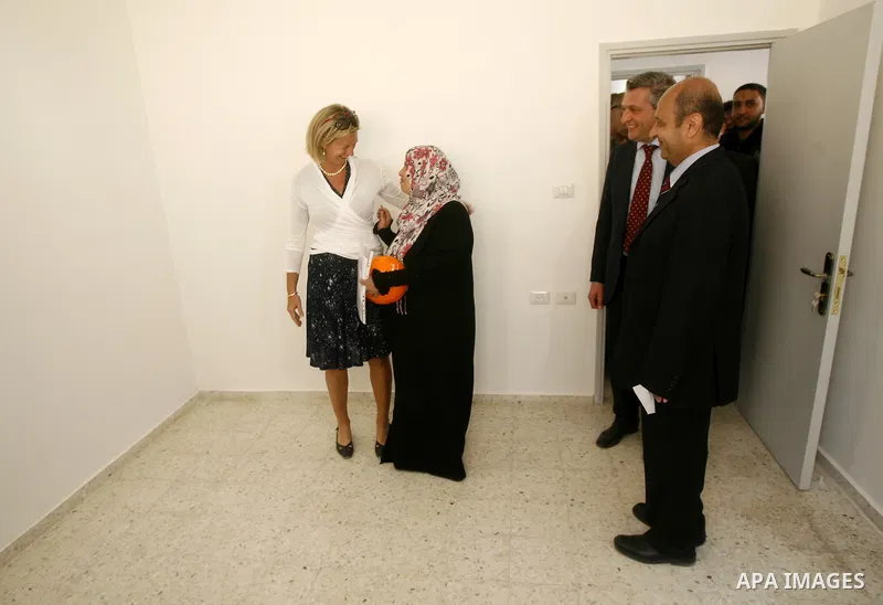 Birgitta Tazelaar head of the Netherlands Representation to the Palestinian Authority, watches alongside UNRWA's Filippo Grandi as a Palestinian woman prepares to enter her new home, after receving a donation from the Du...