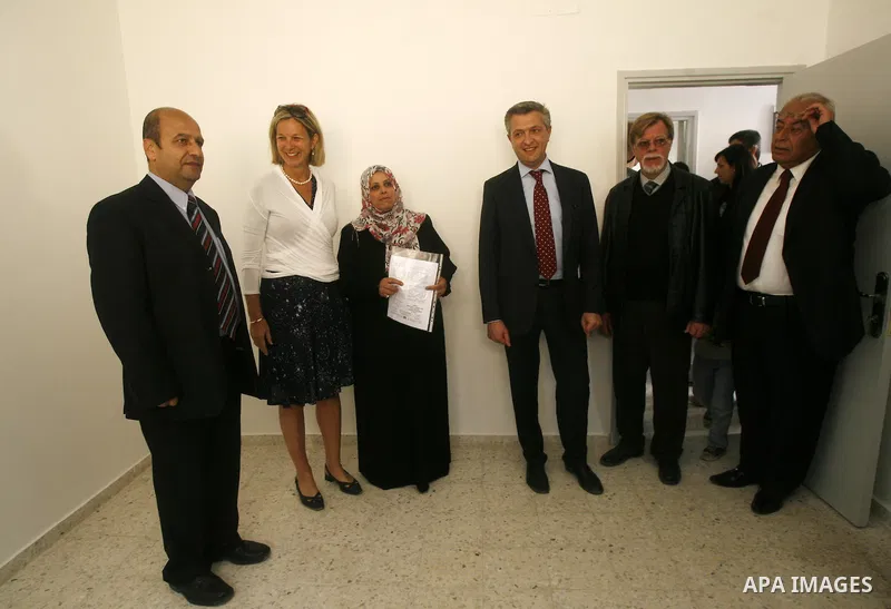 Birgitta Tazelaar head of the Netherlands Representation to the Palestinian Authority, watches alongside UNRWA's Filippo Grandi as a Palestinian woman prepares to enter her new home, after receving a donation from the Du...