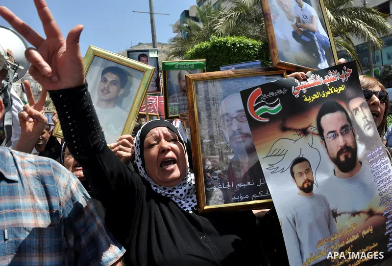 Palestinian woman stands near portraits for prisoners jailed in Israel during a demonstration calling for their release, in the West Bank city of Nablus on April 25, 2012. Photo by Nedal Eshtayah