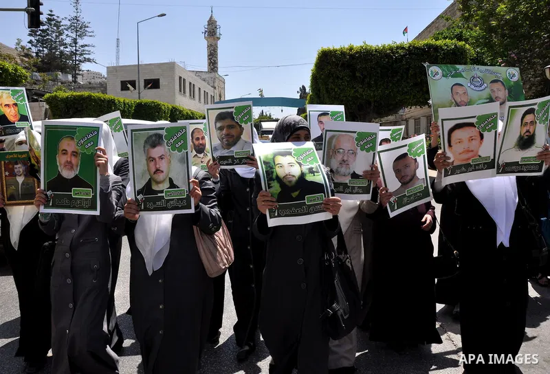 Palestinian woman stands near portraits for prisoners jailed in Israel during a demonstration calling for their release, in the West Bank city of Nablus on April 25, 2012. Photo by Nedal Eshtayah