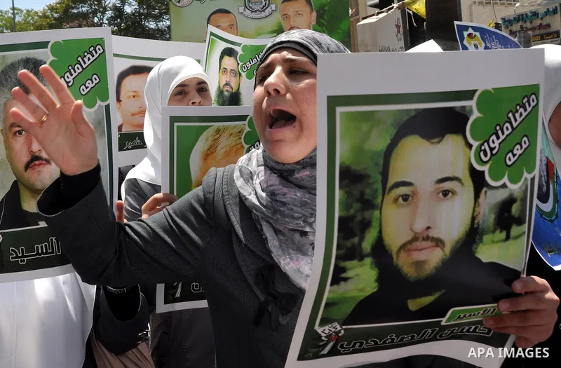 Palestinian woman stands near portraits for prisoners jailed in Israel during a demonstration calling for their release, in the West Bank city of Nablus on April 25, 2012. Photo by Nedal Eshtayah