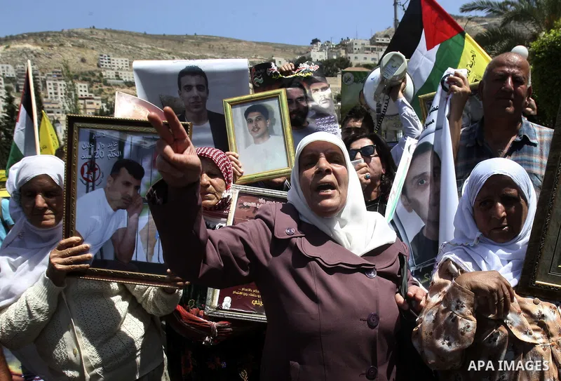 Palestinian woman stands near portraits for prisoners jailed in Israel during a demonstration calling for their release, in the West Bank city of Nablus on April 25, 2012. Photo by Wagdi Eshtayah