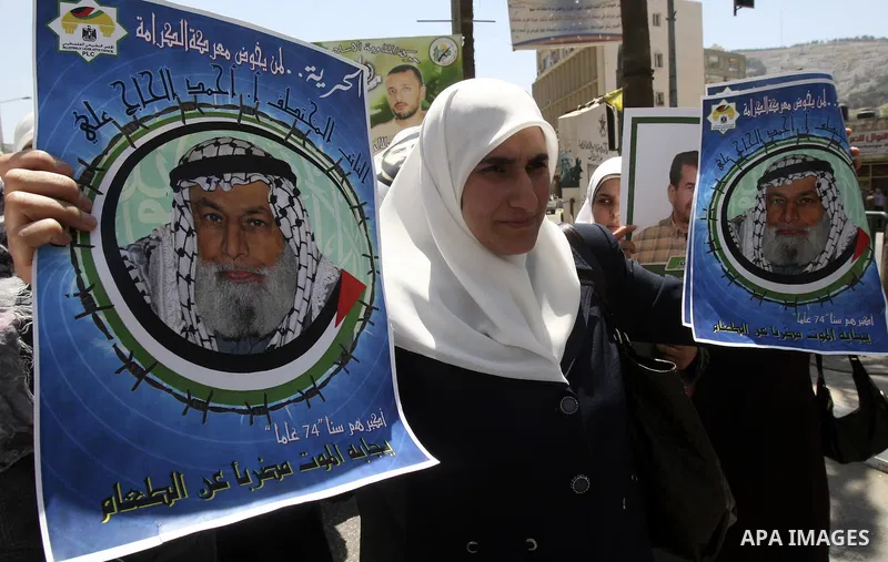 Palestinian woman stands near portraits for prisoners jailed in Israel during a demonstration calling for their release, in the West Bank city of Nablus on April 25, 2012. Photo by Wagdi Eshtayah