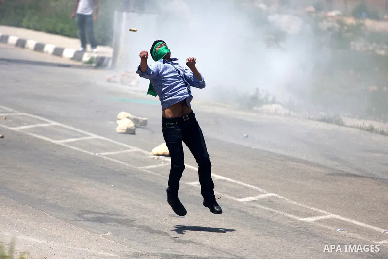 Palestinians hurl stones at an Israeli jeep during clashes with Israeli soldiers at the Bitwonia crossing outside the Israeli military prison of Ofer, on Israel's 64th Independence Day, 26 April 2012. Palestinians staged...