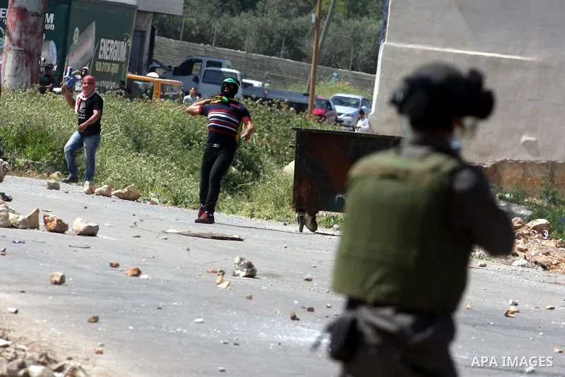 An Israeli soldier fires rubber bullets at Palestinian protesters during clashes at the Bitwonia crossing outside the Israeli military prison of Ofer, on Israel's 64th Independence Day, 26 April 2012. Palestinians staged...