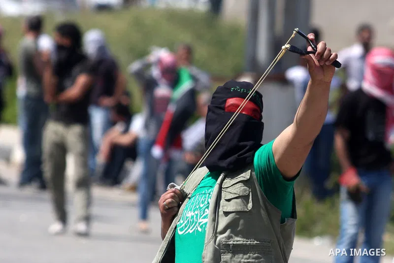 Palestinians hurl stones at an Israeli jeep during clashes with Israeli soldiers at the Bitwonia crossing outside the Israeli military prison of Ofer, on Israel's 64th Independence Day, 26 April 2012. Palestinians staged...