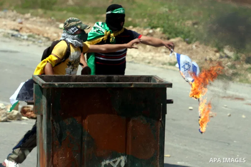 Palestinians burn israel flag during clashes with Israeli soldiers at the Bitwonia crossing outside the Israeli military prison of Ofer, on Israel's 64th Independence Day, 26 April 2012. Palestinians staged their protest...